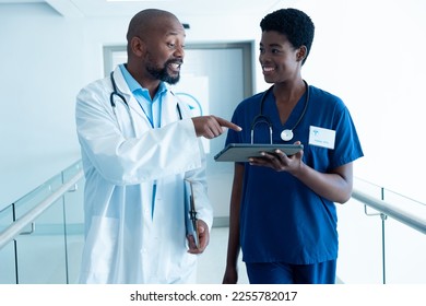 Smiling african american male and female doctor using tablet, talking in hospital with copy space. Hospital, medical and healthcare services. - Shutterstock ID 2255782017