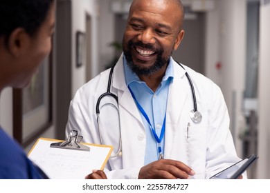 Smiling african american male and female doctor talking in hospital corridor. Hospital, medical and healthcare services. - Shutterstock ID 2255784727