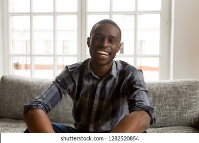 Smiling African American Male Vlogger Life Coach Looking At Camera Sitting On Couch, Positive Friendly Black Millennial Single Man Talking Making Video Call Vlog At Home, Dating Online, Portrait