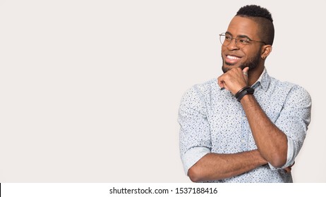 Smiling african American man in glasses isolated on grey studio background look at blank copy space vacant advertising place thinking, happy biracial male in spectacles pondering over good sale offer - Powered by Shutterstock