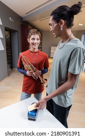 Smiling African American Man Paying With Credit Card Near Girlfriend With Trumpet In Music Store