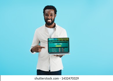 Smiling African American Man Pointing At Laptop With Sports Bet Website Isolated On Blue