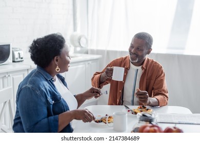 Smiling African American Man Talking With Senior Wife During Breakfast