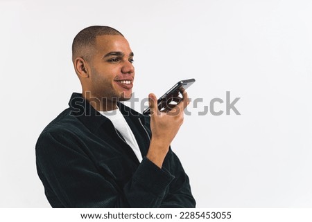 Smiling African American man talking on a speakerphone on a white studio background. High quality photo