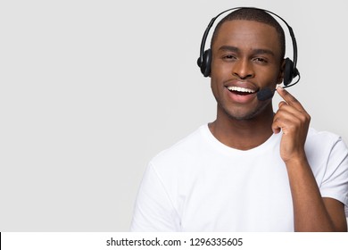 Smiling African American Man Wearing Wireless Headset Talking To Microphone Looking At Camera Isolated On White Background With Copy Space, Black Call Center Operator, Customer Service Agent Portrait