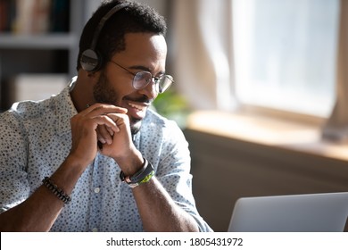 Smiling African American man wearing headphones speaking close up, using laptop, looking at screen, teacher holding online lesson, friendly call center customer service operator consulting client - Powered by Shutterstock