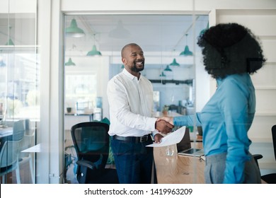 Smiling African American manager shaking hands with a new job applicant after an interview while standing together in his office 