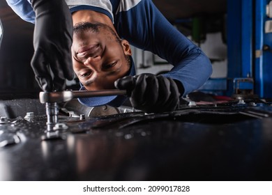 Smiling african american mechanic in gloves working with wrench and car in service