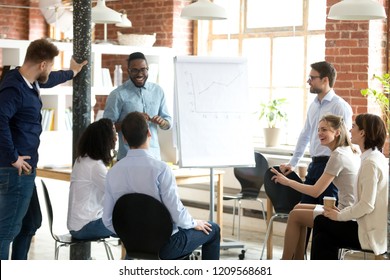 Smiling African American mentor or coach make flipchart presentation for diverse employees, excited black presenter present project on whiteboard, coworkers laugh having fun at casual briefing - Shutterstock ID 1209568681