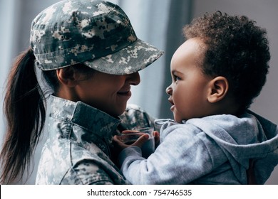 smiling african american mother in military uniform with her little son at home - Powered by Shutterstock