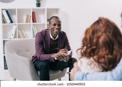 Smiling african american psychiatrist talking to young couple - Shutterstock ID 1050440903
