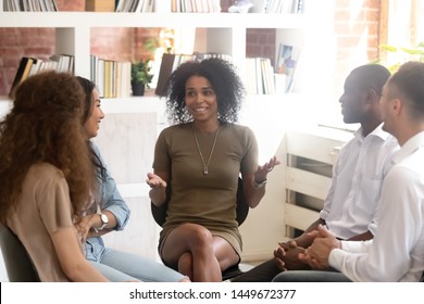 Smiling African American psychologist counselling, speaking with diverse people sitting in circle at group therapy session, business coach training staff, having fun, team building activity at work - Powered by Shutterstock