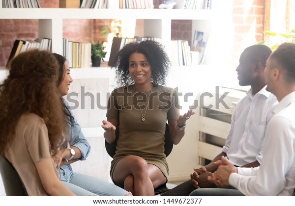 笑顔のアフリカ系アメリカ人心理学者カウンセリング グループセラピーのセッションで輪を作って座る多様な人々 ビジネスコーチの研修スタッフ 楽しく 仕事でチームを作る活動 の写真素材 今すぐ編集 1449672377