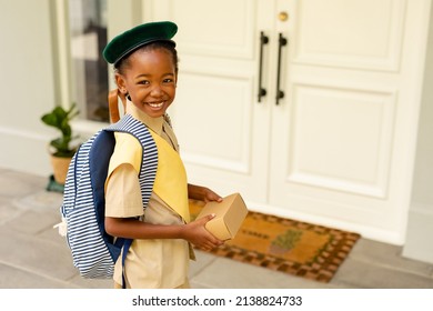 Smiling african american scout girl in uniform delivering package at home. unaltered, girl scout, childhood, courage, leadership, delivery and scouting. - Powered by Shutterstock