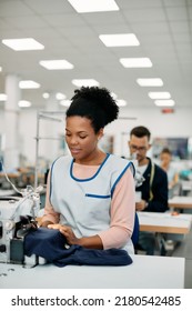 Smiling African American Seamstress Sewing At Clothing Design Studio. 