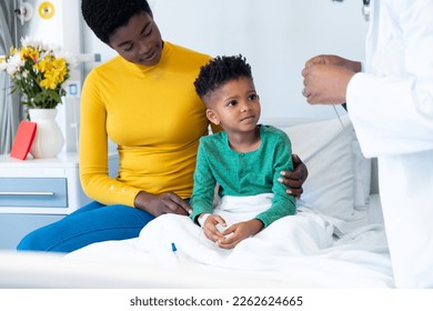 Smiling african american son patient with mother and male doctor in hospital. Hospital, medical and healthcare services. - Powered by Shutterstock