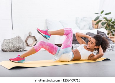 Smiling African American Sportswoman Doing Abs On Fitness Mat In Bedroom At Home