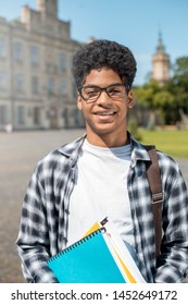 Smiling African American Student In Glasses With Books. Happy Mixed Race Guy Near College.