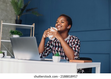 Smiling African American Woman Enjoying Morning Coffee, Sitting At The Desk In The Office. Remote Business. Internet Technology.