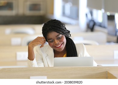 Smiling African American Woman Looking On Laptop. Mature Black Woman In Conversation Using Laptop While Laughing. Young Cheerful Lady Having Fun During A Funny Conversation Video Call.