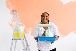 Smiling African American Woman Painting Interior Wall Of Home. Renovation, Repair And Redecoration Concept.