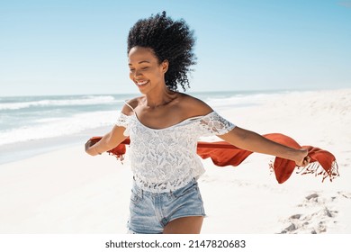 Smiling african american woman running while holding red scarf enjoying at beach. Beautiful happy black woman holding red fabric at wind and running at seaside. Happy woman smiling and having fun. - Shutterstock ID 2147820683