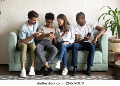 Smiling African American woman show joke on phone to diverse friends, multiracial people using mobile devices together, watching funny video in social network, reading news, look at screen - Powered by Shutterstock