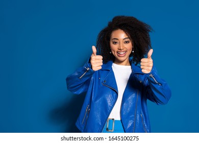 smiling african american woman showing thumbs up on blue background