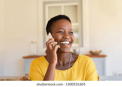Smiling african american woman talking on the phone. Mature black woman in conversation using mobile phone while laughing. Young cheerful lady having fun during a funny conversation call.