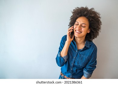 Smiling African American Woman Talking On The Phone. Mature Black Woman In Conversation Using Mobile Phone While Laughing. Young Cheerful Lady Having Fun During A Funny Conversation Call.