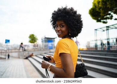 Smiling African american woman using professional camera at a street - Powered by Shutterstock