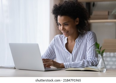 Smiling African American Woman Working On Laptop Online, Confident Businesswoman Or Student Typing Writing Email Or Message In Social Network, Looking At Computer Screen, Sitting At Office Desk