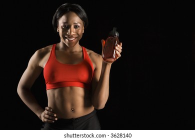 Smiling African American Young Adult Woman Holding Water Bottle With Hand On Hip.