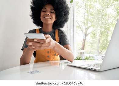 Smiling African American young hipster mixed race gen z young woman with Afro hair holding smart phone scanning QR-code on cafe table to read menu or make mobile payment in cellphone app concept. - Powered by Shutterstock