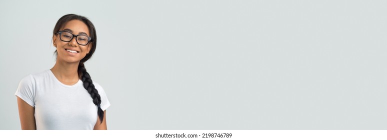 Smiling African American Young Lady In White T-shirt And Eyeglasses Posing Over Grey Background And Smiling At Camera, Studio Shot, Panorama With Copy Space, Collage. Education Concept