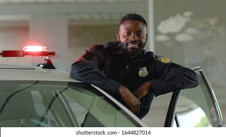 Smiling African American Young Man Cops Stand Near Patrol Car Look At Camera Enforcement Happy Officer Police Uniform Auto Safety Security Communication Control Policeman Close Up Slow Motion