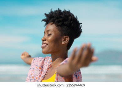 Smiling african american young woman with eyes closed and arms outstretched against sky on sunny day. short hair, summer, happy, unaltered, beach, lifestyle, enjoyment and holiday concept. - Shutterstock ID 2155944409
