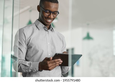 Lächelnder afrikanischer Geschäftsmann, der mit einem Tablet in einem Büro arbeitet