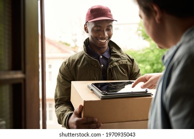 Smiling African Courier Getting A Customer's Digital Signature For A Delivery