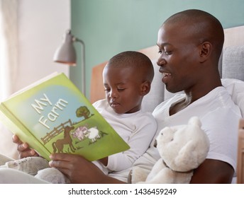 Smiling African Dad Reading To His Child In Bed, Father And Son Bonding Family Time