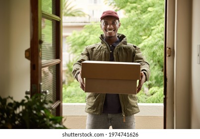 Smiling African Delivery Man Holding Packages At A Front Door