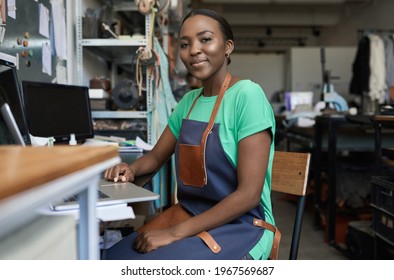 Smiling African female artisan using a laptop in her workshop - Powered by Shutterstock