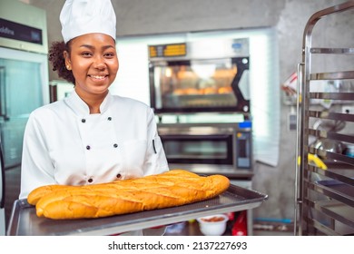 Smiling african  female bakers looking at camera..Chefs  baker in a chef dress and hat, cooking together in kitchen.Professional cooks in uniform preparing meals for a restaurant. - Powered by Shutterstock