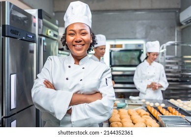 Smiling african  female bakers looking at camera..Chefs  baker in a chef dress and hat, cooking together in kitchen.Team of professional cooks in uniform preparing meals   in the kitchen. - Powered by Shutterstock