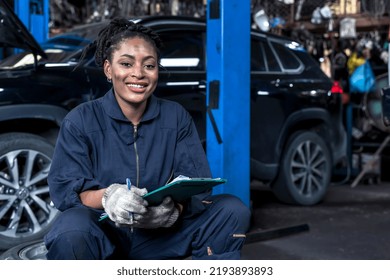 Smiling African Female Car Mechanic Holding Customer Chart Working In Auto Repair Service Shop,black Woman Mechanic Checking Car Problem Lists In Vehicle Garage , Automobile Repair Service Concept