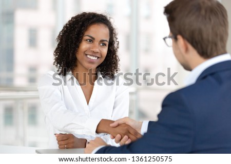 Smiling african female hr manager handshake hire male candidate at job interview make good first impression, happy mixed race client shake hand of bank broker, respect, business agreement concept
