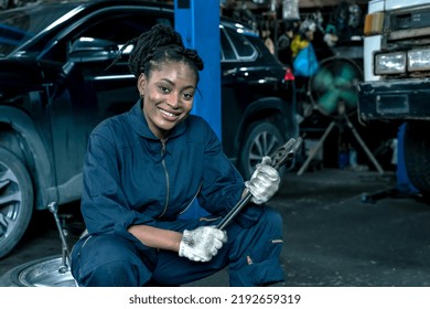 Smiling African female mechanic holding wrench working in car repair auto service - Powered by Shutterstock