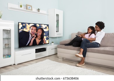 Smiling African Mother And Daughter Having Fun While Watching Television At Home