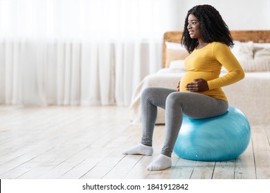 Smiling African Pregnant Lady With Big Tummy Sitting On Fitness Ball In Bedroom, Looking At Copy Space. Sport During Pregnancy. Black Expecting Woman Training On Ball, Getting Ready For Childbirth