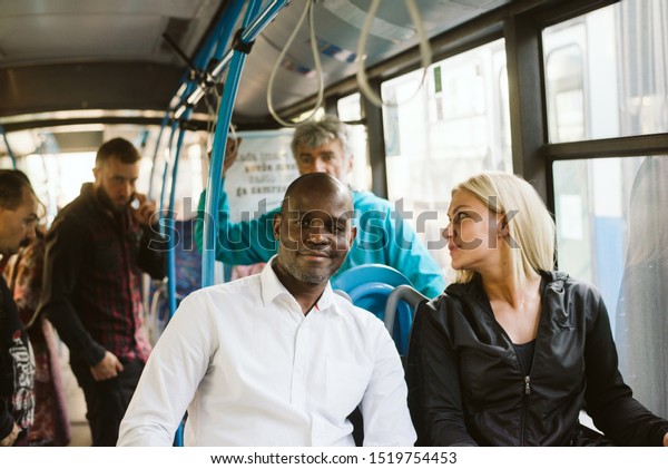 A smiling African rides in a public transport and\
looks at the camera